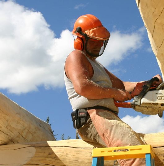 man building log cabin