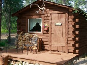 Bear's Den log cabin with chairs and plenty of wood outside