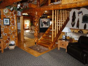 Interior view of cabin with wood stairs leading up from sitting room