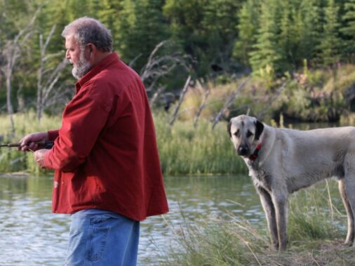 Man fishing with dog nearby