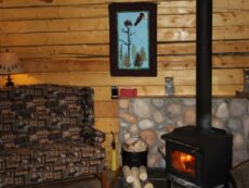 Woodburning stove in Eagle's Nest cabin with comfy chair for relaxing by fire