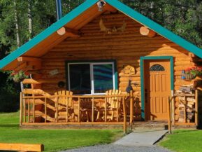 Exterior of Wolf's Den cabin with rockers on porch and plenty of stacked firewood