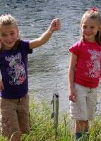 two smiling girls, one holding fish