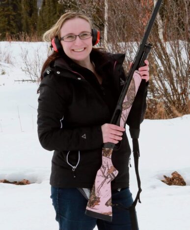 Smiling lady holding rifle in snow