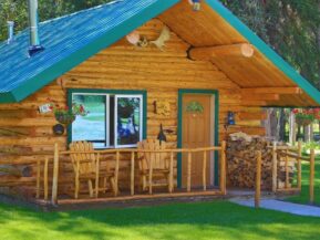 Exterior of Wolf's Den cabin with rockers on porch and plenty of stacked firewood